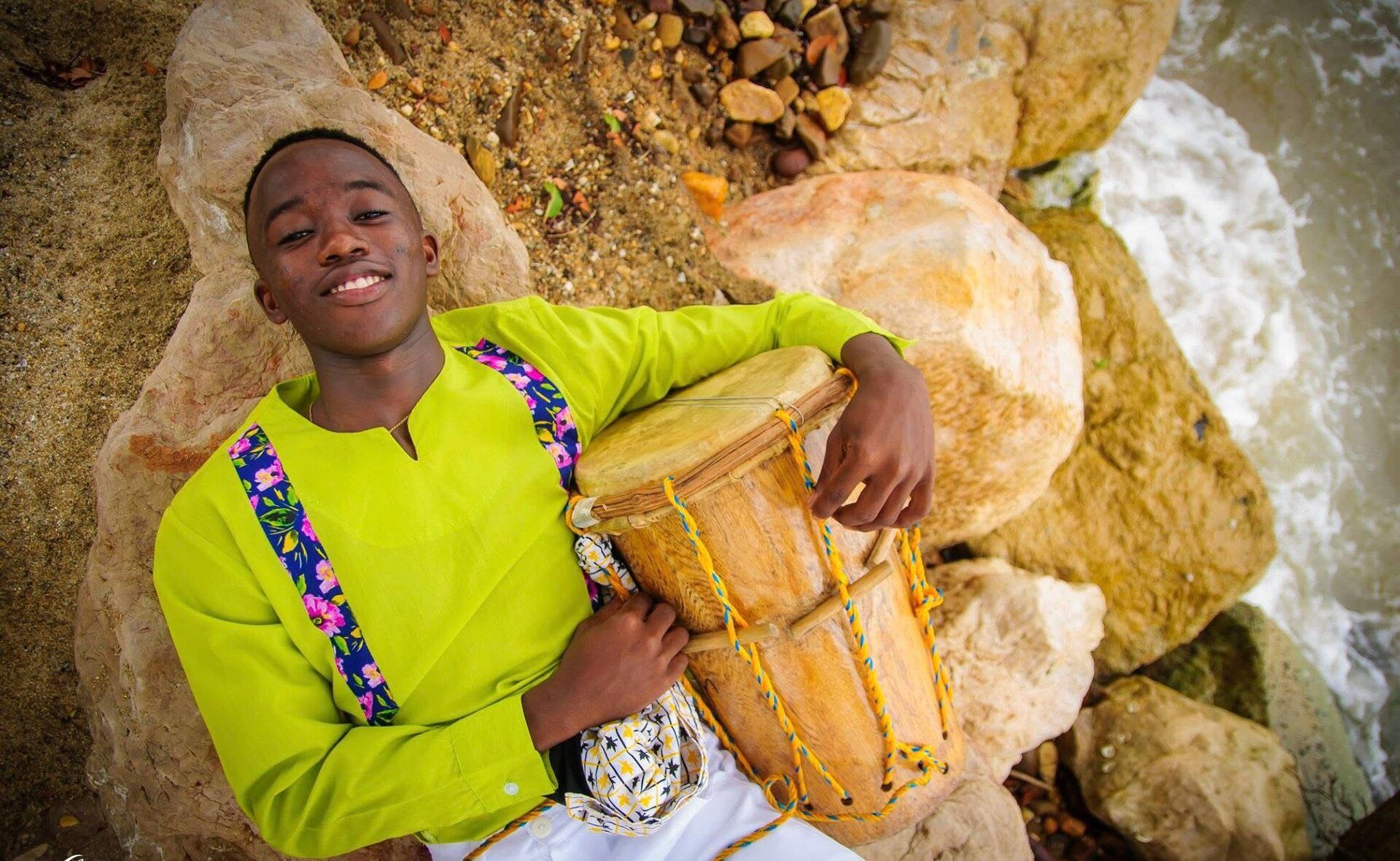 Garifuna teenager holding drums beside the sea in Dangriga