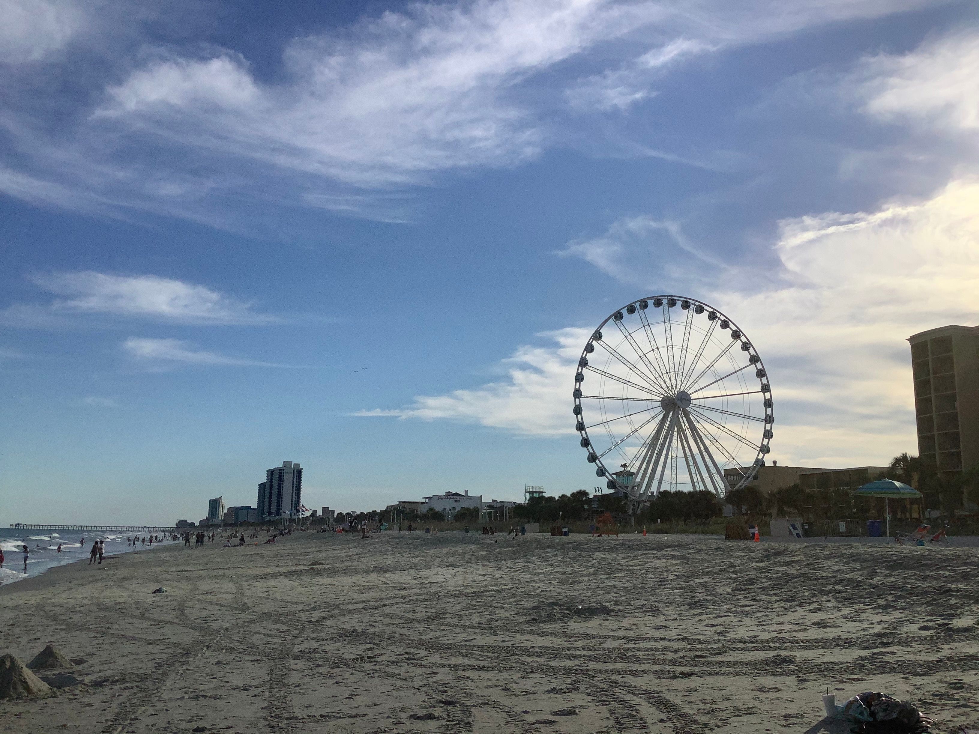 The SkyWheel seen from the beach on a summer afternoon, with beachgoers and oceanfront hotels alongside; venue-area landmark context, not the event.