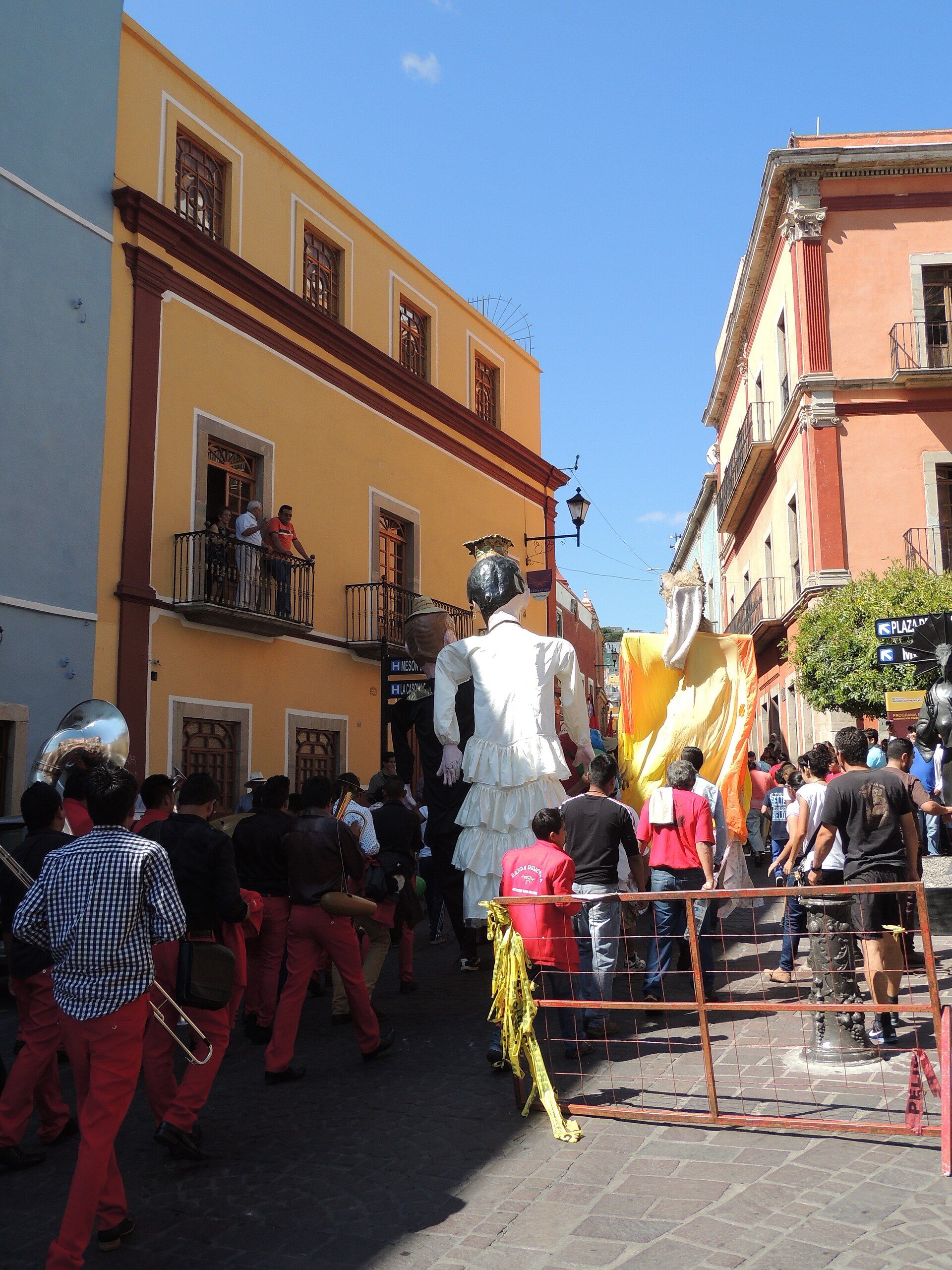 A Cervantino parade moving through a colorful Guanajuato street