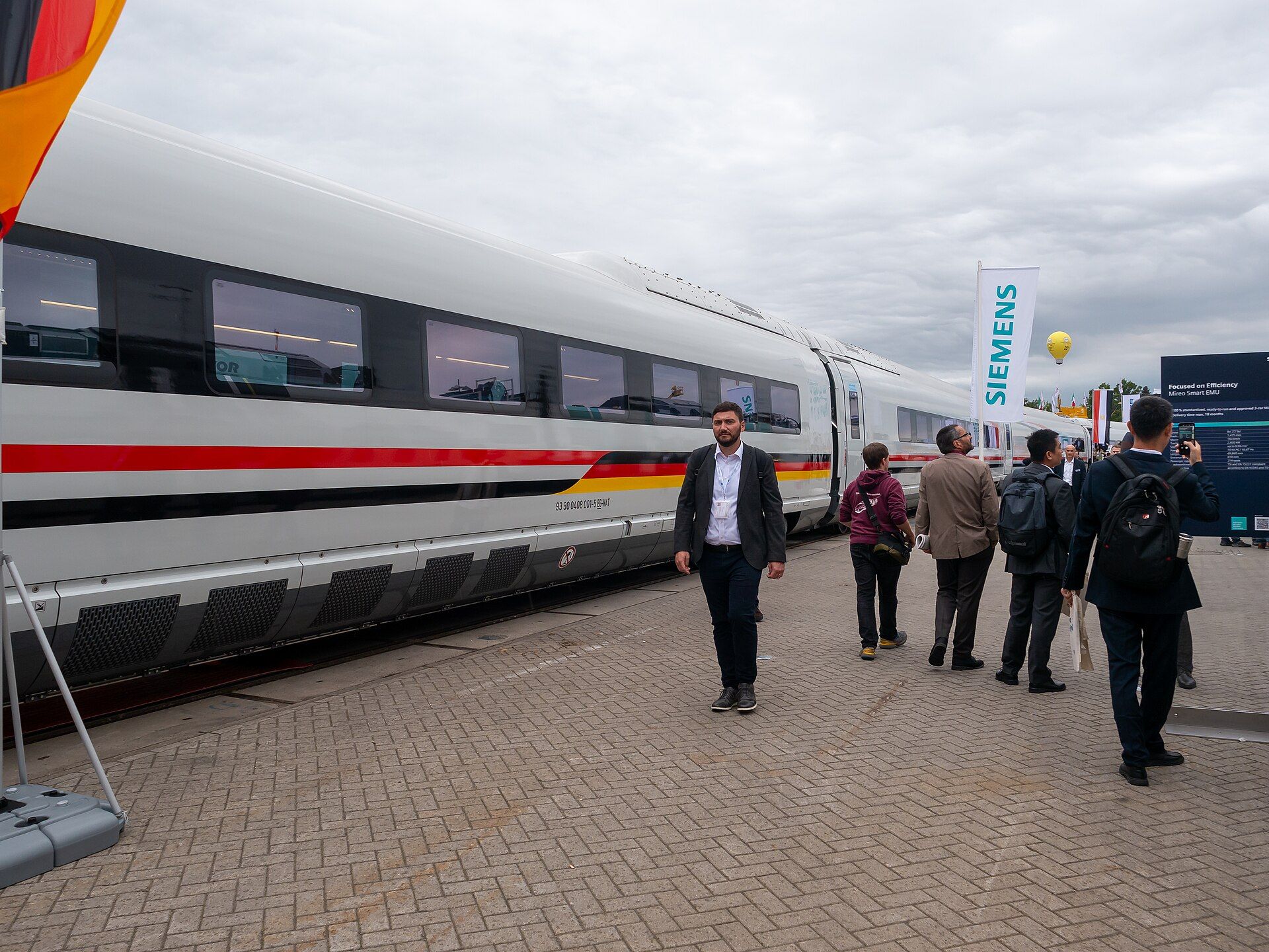 Trade visitors walking beside a full-size high-speed train at InnoTrans 2024