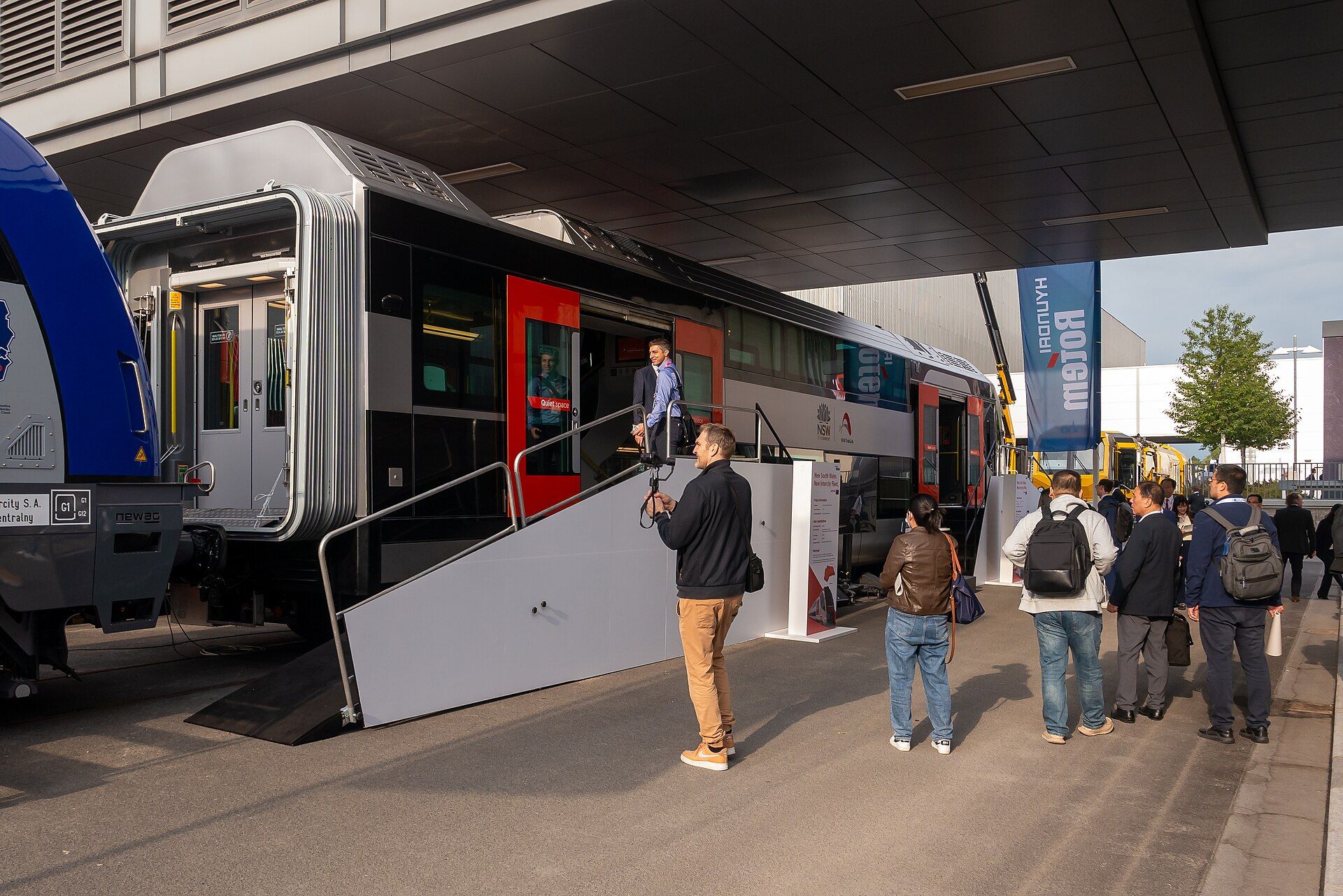 Trade visitors inspecting a full-size rail vehicle on the InnoTrans outdoor track display in 2024