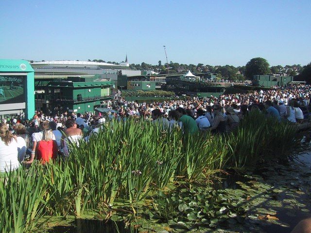 Spectators gathered on Henman Hill watching tennis on the big screen, photographed during a past Wimbledon Championships. Crowd atmosphere photo, not the 2027 event.